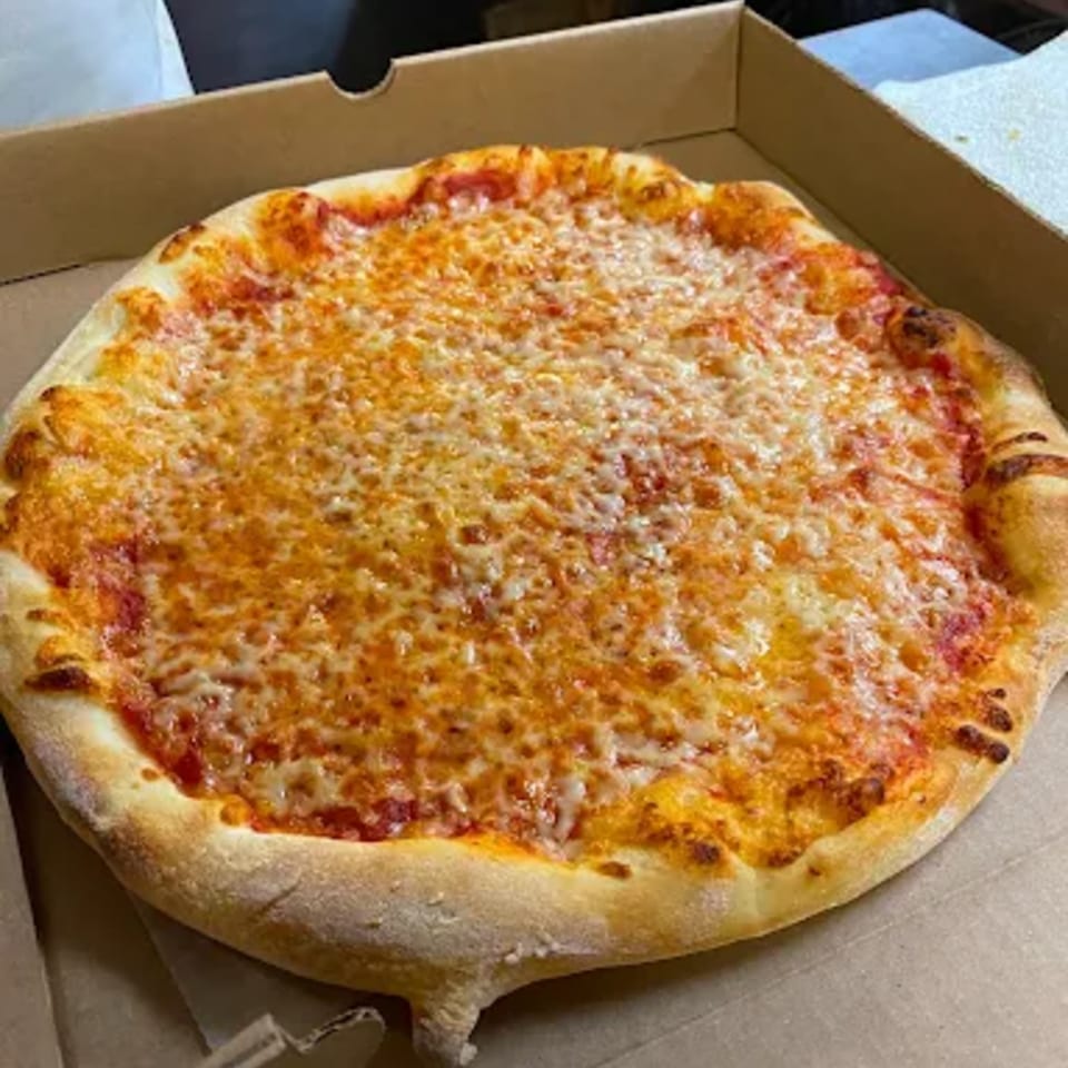 A freshly baked cheese pizza with a golden crust sits in a cardboard delivery box.